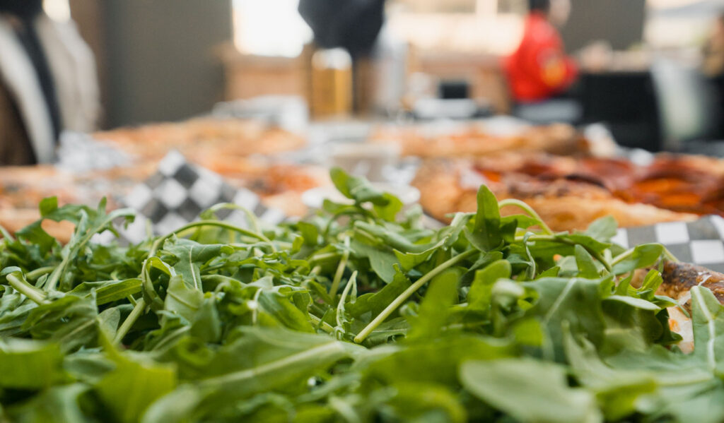 Close up of an arugula-topped thin crust pizza.